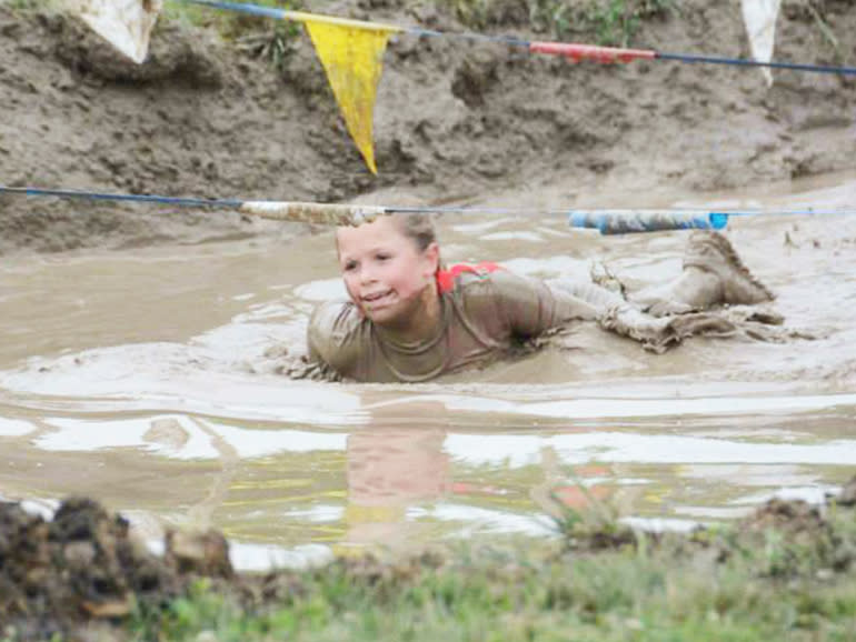 A girl crawling through a pit of watery mud