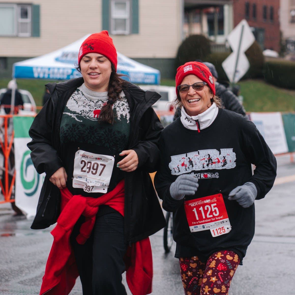 Two woman wearing red hats cross the finish line.
