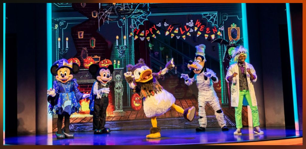Costumed characters perform on stage with Halloween decorations and a festive backdrop, celebrating Halloween with cheerful expressions and vibrant costumes.