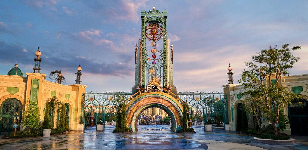 An entrance archway with a rainbow design and the word EPIC, surrounded by colorful architecture and lush greenery under a blue sky