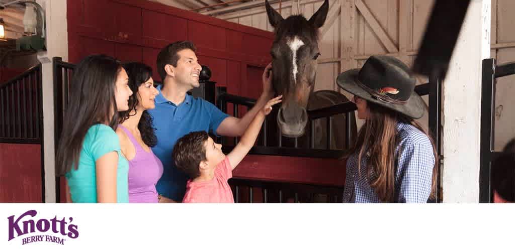 Family petting a horse in a stable with Knott's Berry Farm logo.