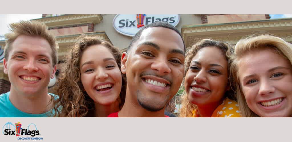 Five people smiling in front of a Six Flags entrance.