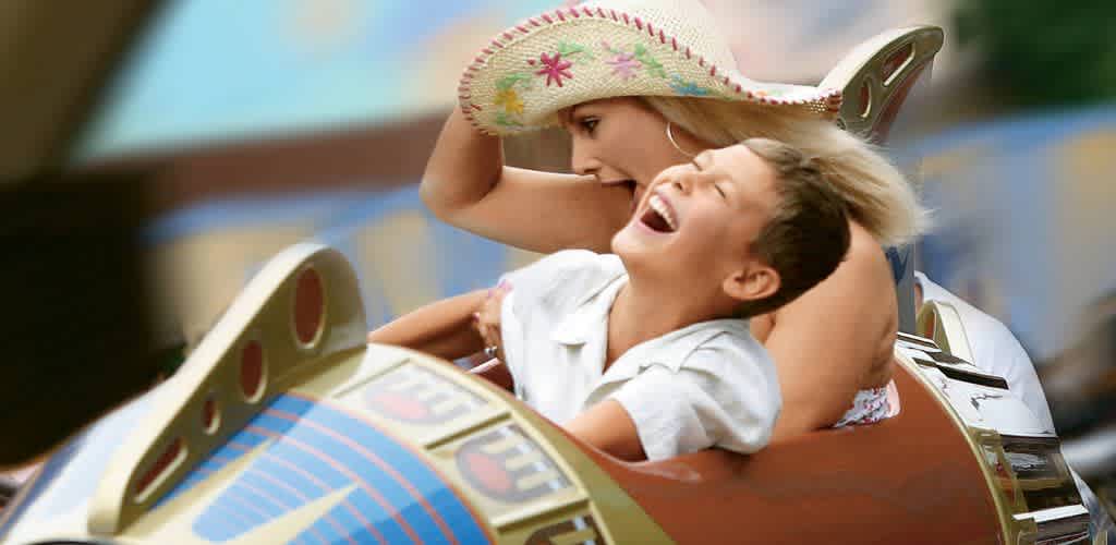 A woman and a boy ride a carnival ride with a sombrero, laughing and enjoying the fun together.