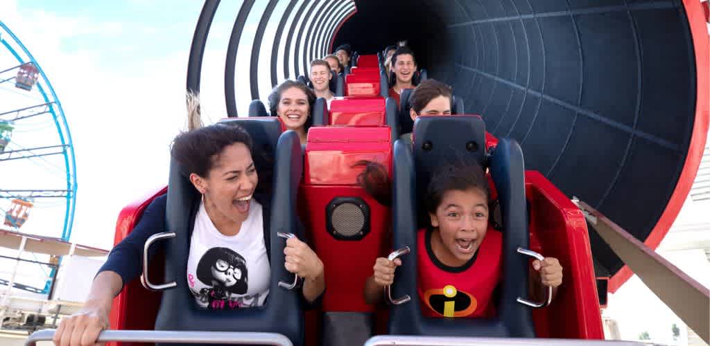 Group of excited people riding a roller coaster at an amusement park with bright smiles and open mouths