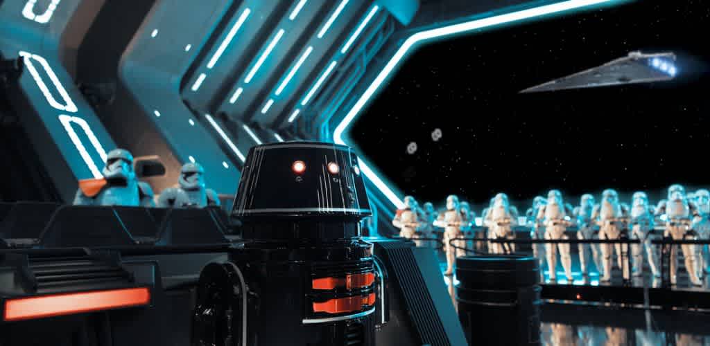 A futuristic spaceship interior features uniformed soldiers and robotic figures. The space is dimly lit with blue accents, and large windows reveal a star-filled sky and a spacecraft in the distance. The scene conveys a high-tech, sci-fi atmosphere with a focus on technology and exploration.