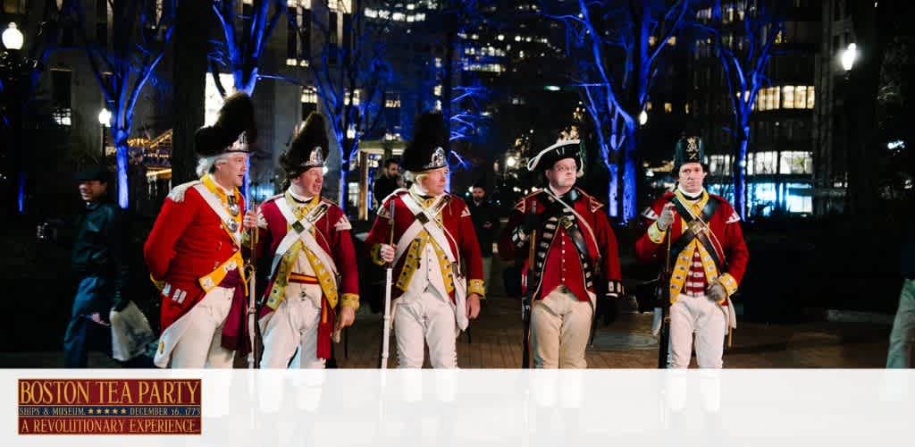 Five individuals in historical military attire, including tricorne hats, walk side by side at night with illuminated trees in the background. Text below references the Boston Tea Party and a related museum experience.