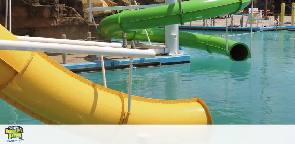 Yellow and green water slides at a water park leading into a swimming pool.