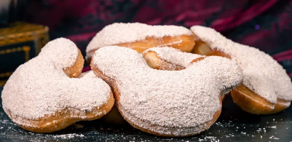 Close-up of heart-shaped cookies dusted with powdered sugar on a dark surface with a blurred background.