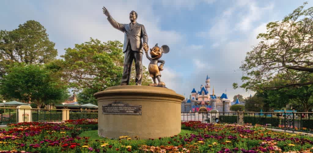 Statue of Walt Disney holding hands with Mickey Mouse in front of Sleeping Beauty Castle at Disneyland Park