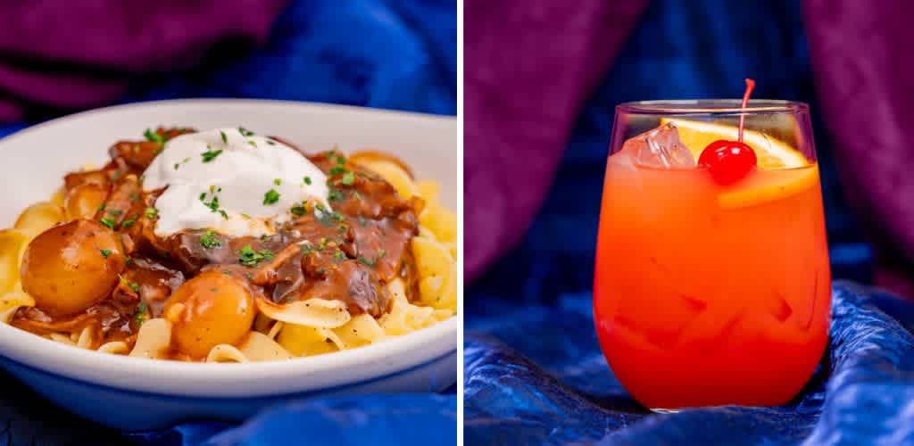A plate of pasta topped with a rich, creamy sauce, garnished with small potatoes and herbs, alongside a vibrant, orange-pink drink in a glass with a cherry and lemon slice. The backdrop is a luxurious blue and purple fabric setting, enhancing the appetizing and inviting presentation of the dish and drink.