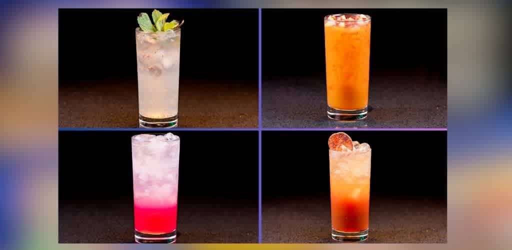 Four tall glasses with various colorful beverages are arranged in a grid. The top left drink is clear with mint leaves. The top right is orange. The bottom left is pink with a gradient. The bottom right is reddish-orange with a citrus slice garnish. Each stands against a dark background highlighting their vibrant colors.