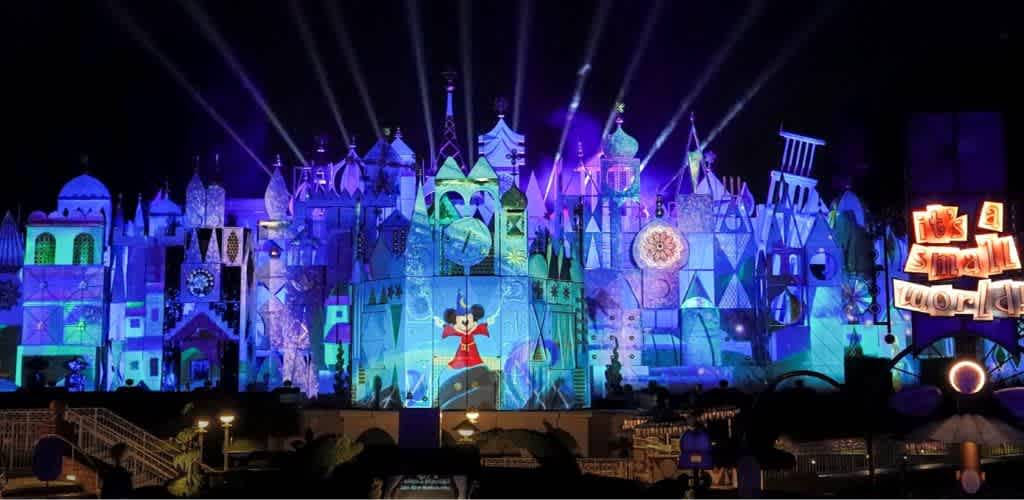 Colorful illuminated castle at night with animated characters and bright lights for a Disney theme park show