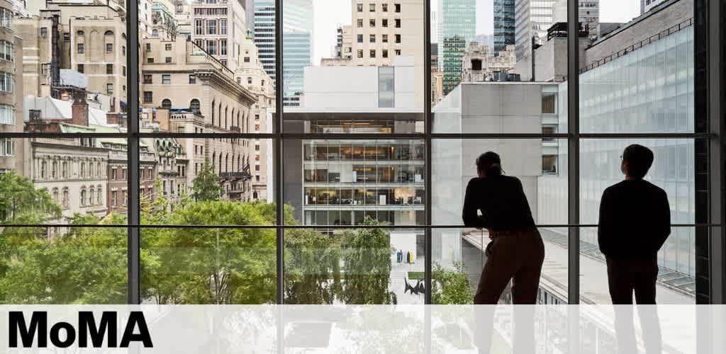 Image shows a view from inside a building looking out onto a cityscape with abundant green trees. In the foreground, two people are silhouetted against large, clear windows, observing the scene. The building's interior and urban environment outside are illuminated by natural light. Text indicating 'MoMA' is visible at the bottom.