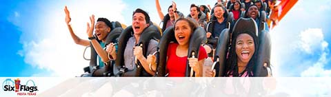 Image shows a group of excited people on a roller coaster, arms raised in thrill, with a bright blue sky in the background. Six Flags logo is visible, indicating the amusement park.