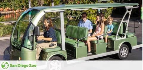 Image shows a green, multi-passenger electric cart at the San Diego Zoo with a driver in uniform and four passengers. Two adults and two children appear to be enjoying a tour, with lush greenery in the background. The San Diego Zoo logo is visible in the corner.