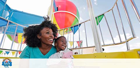 A woman and child enjoy a ferris wheel ride under a blue sky.