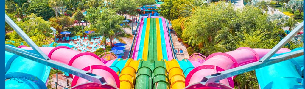 Colorful water park slides surrounded by lush greenery, viewed from above.