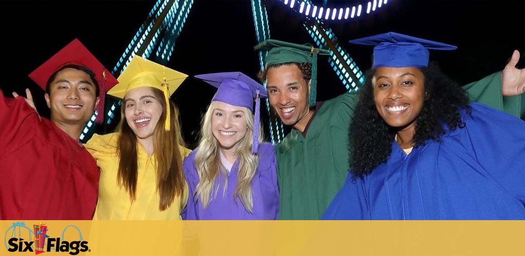 Image with five happy graduates in colorful caps and gowns with their arms around each other, smiling widely. They are in front of a vibrant night scene with a roller coaster track lit up in the background. The Six Flags logo is at the bottom left.