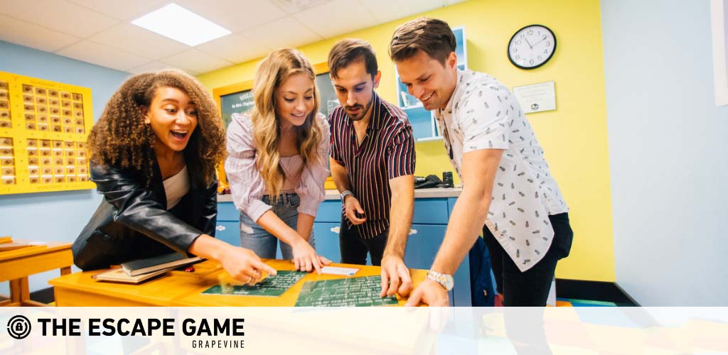 Four individuals are engaged in a puzzle at The Escape Game Grapevine. They're leaning over a table covered with clues, displaying excitement and collaboration. Brightly hued room with elements hinting at an interactive challenge.