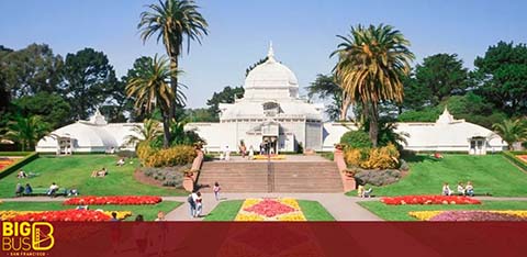 This is an image of a serene park setting, featuring a central white building with a prominent dome and surrounding smaller structures, all with a similar architectural style. There is a staircase leading up to the main entrance of the building. The park is well-manicured with symmetrical flower beds showcasing vibrant blooms in red, yellow, and purple colors. Tall palm trees tower on either side of the scene, adding to the tranquility. Visitors are scattered around the garden, some sitting on the grass and others walking along the pathways. The weather appears to be sunny and pleasant. In the bottom portion of the image, there's a watermark or logo that reads "BIG BUS."

At FunEx.com, explore a variety of destinations and take advantage of our exclusive offers, where you'll find the lowest prices on tickets, ensuring your adventures come with both significant savings and unforgettable memories.