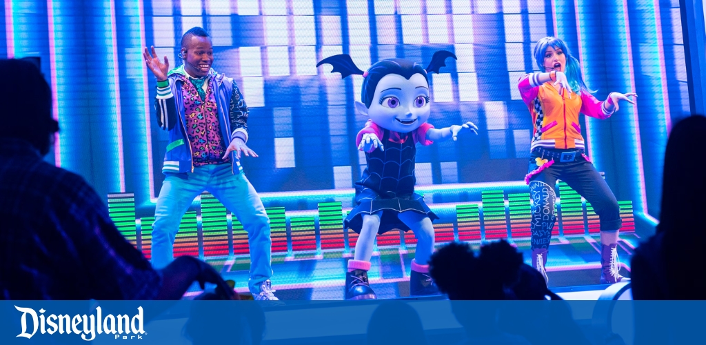 Performers and a character entertain on a vibrant stage at Disneyland Park.