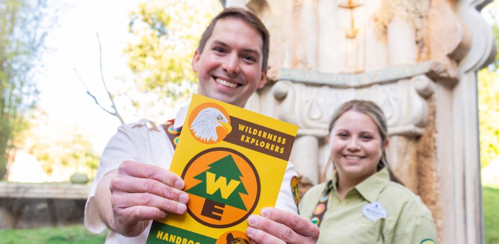 A man and woman proudly display a book featuring the letters 