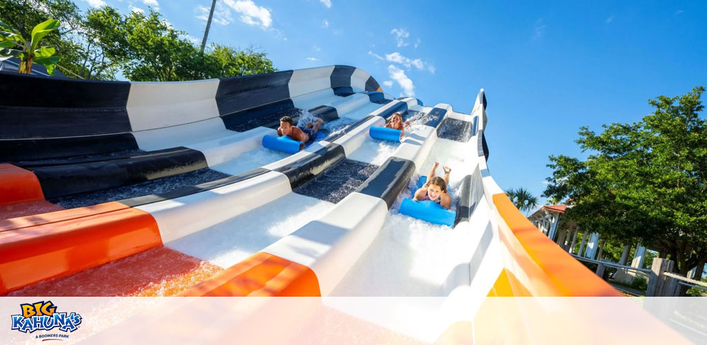 People enjoy a multi-lane water slide under sunny skies.