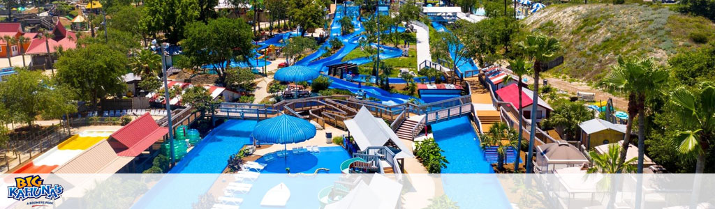 A panoramic view of a colorful water park with slides and pools amidst greenery.