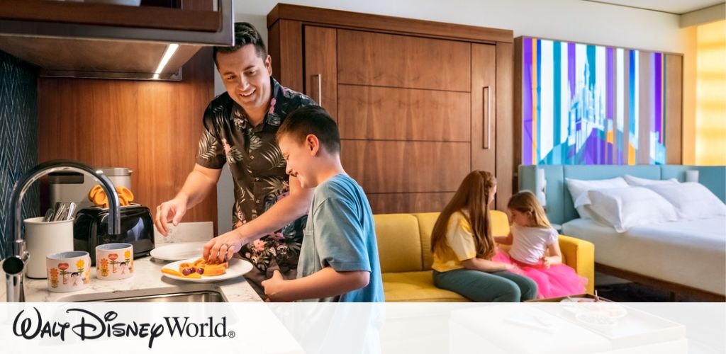 In a cozy hotel room, a man and a boy are preparing a meal at a kitchenette, brightly lit and cheerful. Two girls are sitting on a yellow sofa, engaged in an activity together. The room is stylishly decorated with a colorful wall art and features a neatly made bed. The environment is vibrant and inviting. Walt Disney World logo is visible at the bottom of the image.