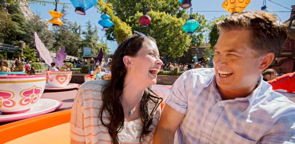 A couple laughing and enjoying the Mad Tea Party teacup ride at Disneyland Park.