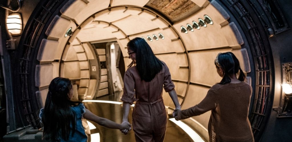 A mother and her daughters exploring the Millennium Falcon interior at Star Wars: Galaxy’s Edge in Disneyland.