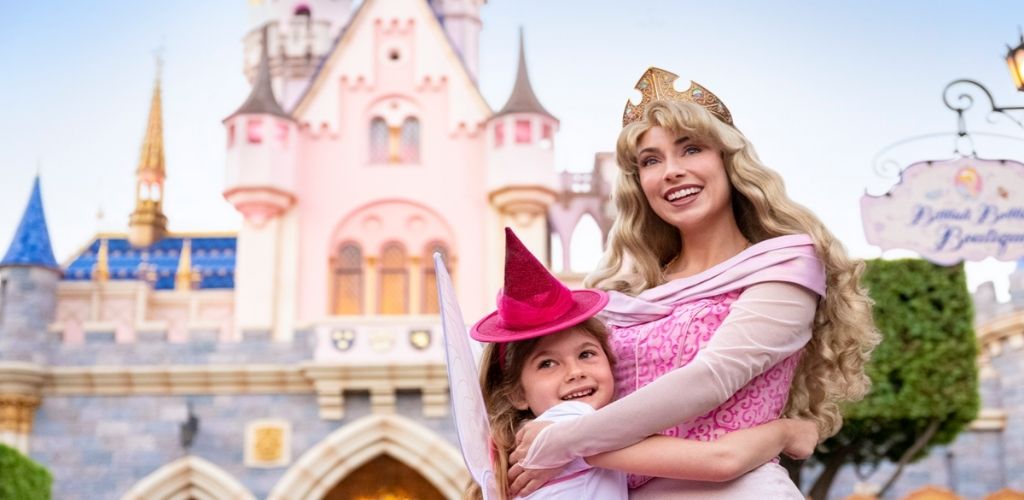 A little girl dressed as a princess meeting Princess Aurora in front of Sleeping Beauty Castle at Disneyland.