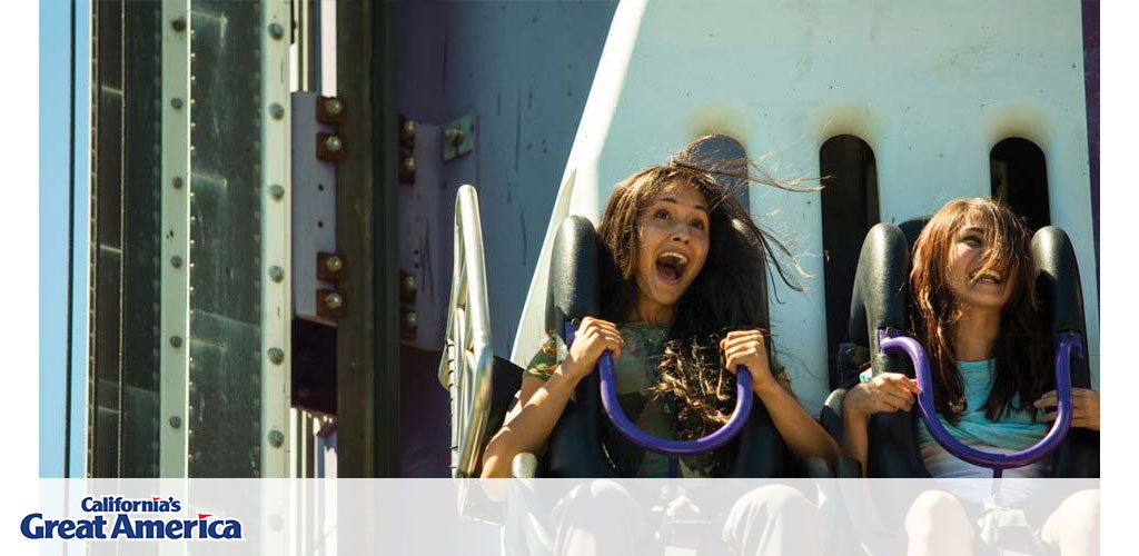 This image captures the thrilling excitement of two individuals riding a roller coaster at California's Great America theme park. Both riders appear to be holding onto the safety bars of their seats with glee and exhilaration, their hair wildly tossed by the wind as they descend at high speeds. Bright sunlight bathes the scene, highlighting the riders' expressions of joy and the dynamic energy of the moment. The backdrop shows a blurred view of the roller coaster's structure, emphasizing the speed of the ride.

Capturing the essence of adventure and fun, this photo invites viewers to experience the heart-pounding enjoyment of amusement park attractions. And remember, if you're looking for heart-racing fun at a fraction of the cost, FunEx.com offers discounts and savings on tickets so you can enjoy the lowest prices for your next thrilling adventure!