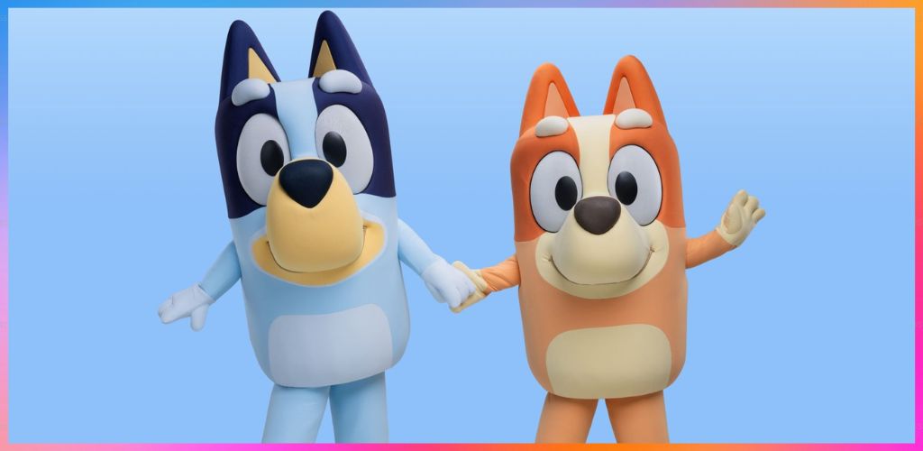 Costumed characters of a blue and white dog and an orange and cream dog holding hands and waving on a light blue background.