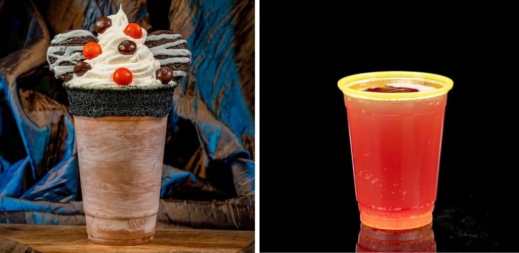 A chocolate milkshake with whipped cream, chocolate candies, and a chocolate drizzle on top next to a red fruit flavored drink in a clear cup with a yellow rim