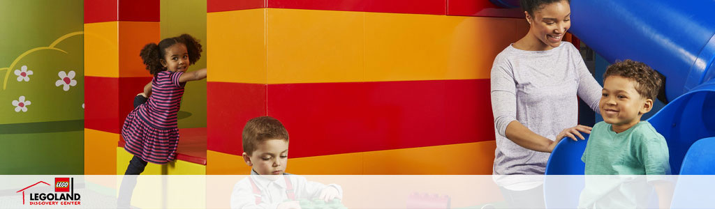 Image showing a joyful atmosphere at LEGOLAND Discovery Center. On the left, a child in a striped dress is climbing a colorful structure with LEGO-inspired designs. In the center, a boy is engaged in play with bright LEGO blocks. To the right, a woman watches a cheerful child emerging from a blue slide. Excitement and interactive play are evident throughout.