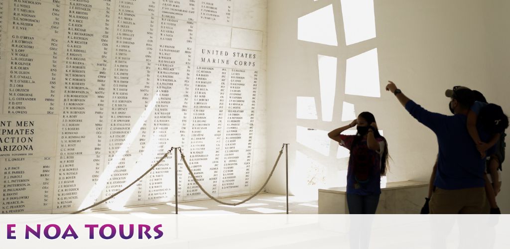 Visitors examine a memorial wall listing names, with sunlight casting geometric patterns through a window. The text  E NOA TOURS  is overlayed in the bottom corner.