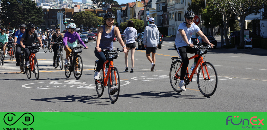 This image captures a lively scene of outdoor activity, with a group of people enjoying a bike ride on a sunny day. The cyclists, wearing various casual athletic attire and safety helmets, are riding on a marked bike path along a city street. The forefront shows a cyclist smiling broadly, indicating the enjoyable nature of the activity. Lush green trees line the sidewalk under a bright blue sky, and classic city architecture is visible in the background. Pedestrians can also be seen walking alongside the bikers, giving the impression of a vibrant and active urban environment.

For GreatWorkPerks.com visitors looking to experience the thrill of city biking, remember that our website offers incredible discounts and savings on tickets for outdoor activities, ensuring you get the lowest prices for your next adventure.