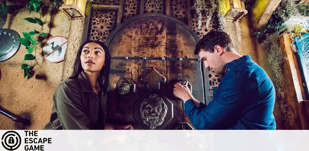 This image showcases two individuals engaged in an activity within an escape room. On the left, a woman is seen peering upward thoughtfully, her expression one of concentration and curiosity. She dons a green, long-sleeve shirt which blends with the theme of the room. The room is adorned with rustic decor and exudes an adventurous ambiance, featuring earthy tones, mysterious symbols on the walls, and low-hanging greenery to add to the atmosphere of intrigue. On the right, a man wearing a dark blue shirt is intently examining an object, illustrating the active problem-solving aspect characteristic of escape room challenges. Both participants are immersed in the game, surrounded by elements designed to evoke a sense of ancient discovery.

Get ready to dive into a world of mystery and excitement with GreatWorkPerks.com, where you can unlock the secret to incredible savings with discounted tickets to the best entertainment experiences at the lowest prices!