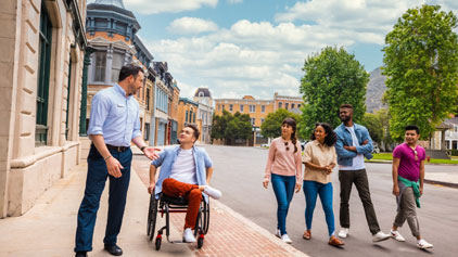 Image Description: A diverse group of six adults is enjoying a walk down a picturesque, tree-lined urban street. The setting appears to be a charming town with European-style architecture visible in the background. The sky is clear and blue, suggesting a pleasant day. One individual is using a manual wheelchair and is engaged in conversation with a man standing to their side, both appearing cheerful. The others in the group are walking behind them, close enough to be part of the group, engaged in their own conversations and carrying smiles on their faces. They are dressed casually, suitable for a relaxed day out with friends.

At GreatWorkPerks.com, we believe memorable experiences should be accessible to everyone, and we offer the lowest prices and best discounts to make it possible. Check out our deals on tickets for your next adventure!