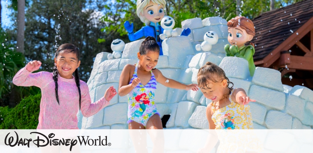 Children playing at a water park with animated statues in the background. They are having fun with water features, smiling and enjoying the sunny day. Trees and a wooden structure are in the background, creating a joyful and vibrant atmosphere.