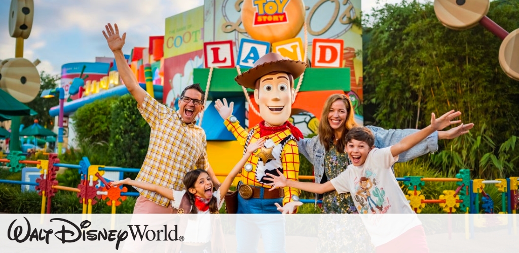 A family happily poses with a cowboy character at an amusement park. They are smiling with arms outstretched in front of a colorful backdrop with oversized toy blocks and greenery, creating a vibrant and playful atmosphere. The theme park setting suggests a fun and engaging adventure for visitors of all ages.