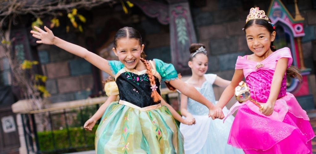Young girls dressed as Disney princesses, enjoying a magical moment at Disneyland Park.