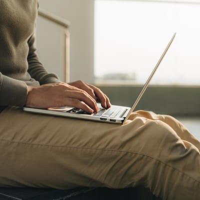 ein Geschäftsmann, der mit dem Laptop auf den Knien sitzt.