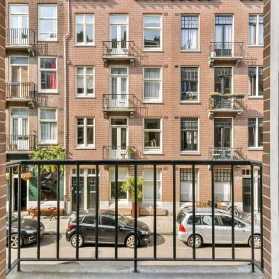  Ein ruhiger Blick von einem Balkon, eingerahmt von modernen Geländern, der die städtische Architektur und die darunter geparkten Autos offenbart.