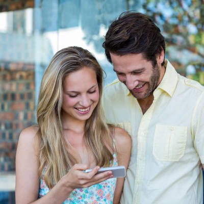 Lächelndes Paar, das in einem Einkaufszentrum auf ein Smartphone schaut