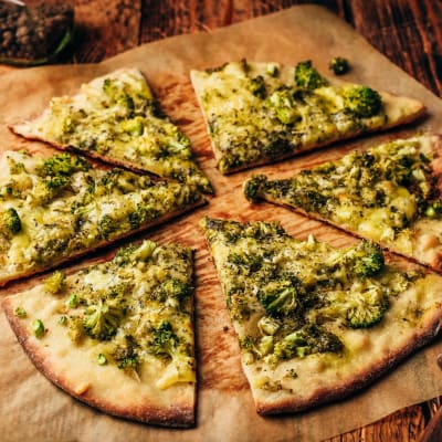 Stücke hausgemachter Pizza mit Brokkoli und Käse auf Backpapier