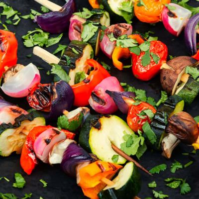 Veganes Schaschlik aus frischem Gemüse am Spieß auf einem rustikalen Holztisch.
