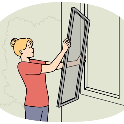 Frau montiert Fliegengitter an einem Hausfenster.