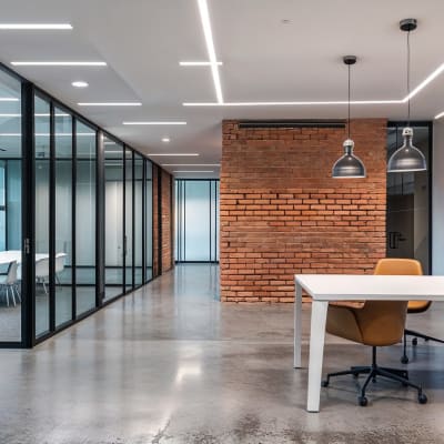 Modernes Büro mit freiliegenden Ziegelwänden, Glastrennwänden und modernen Möbeln